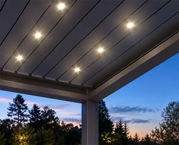 Soffitto a lamelle inclinate di una pergola bioclimatica in metallo scuro, dotata di faretti LED a incasso